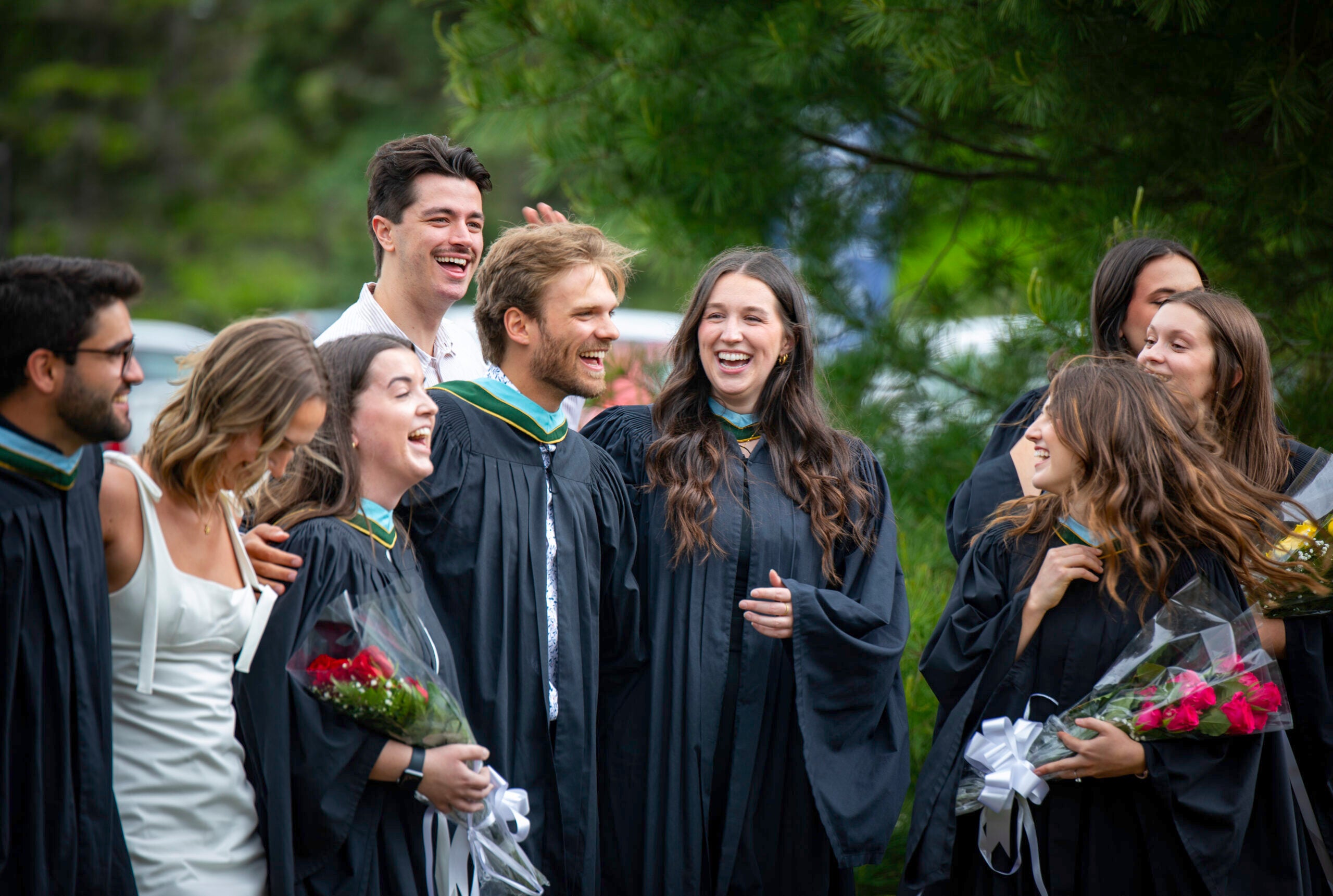 A group of Nipissing graduates in regalia taking pictures and laughing.